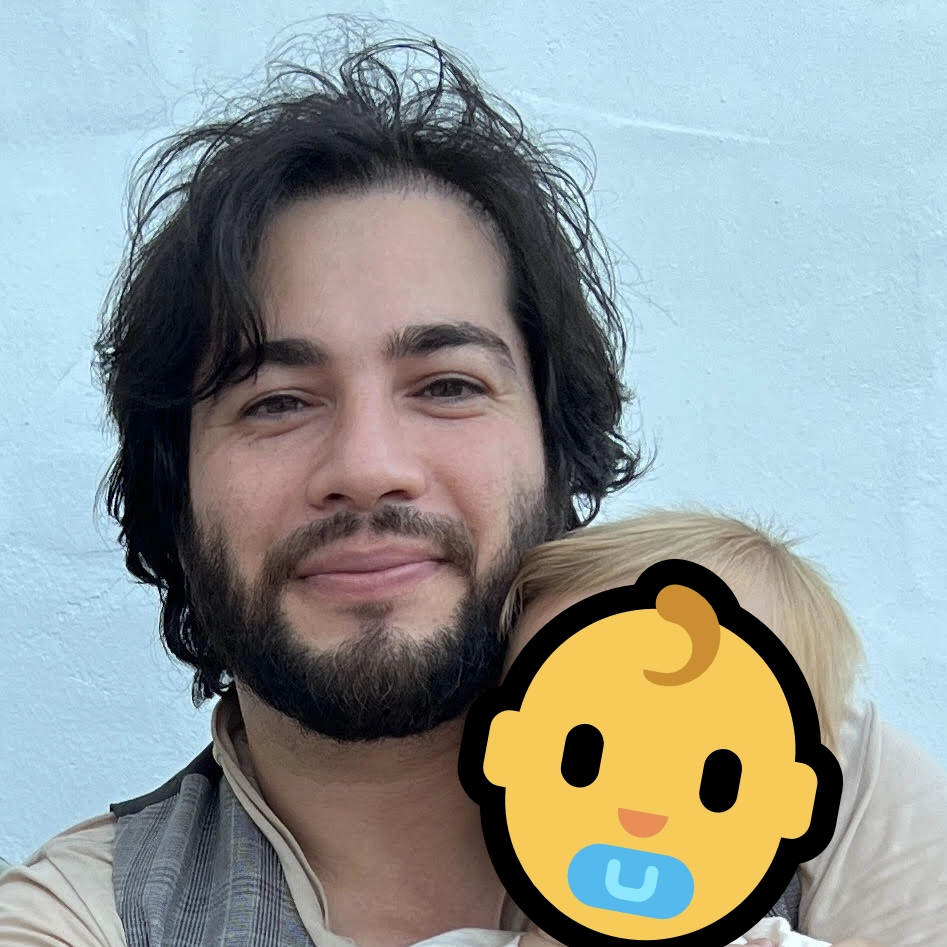 Portrait of MH Mirzazadeh holding a baby with an emoji over his face for the childs privacy